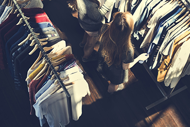 overhead view of clothes racks with woman shopping